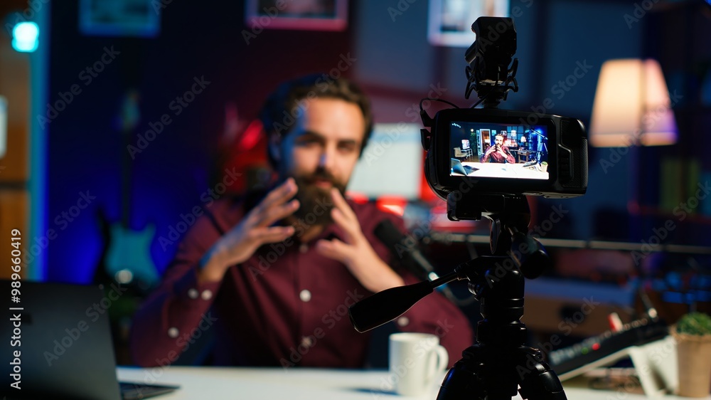 Aufkleber focus on professional camera used by man in blurry background hosting online show in neon lit studio