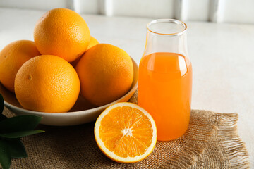 Bottle of fresh orange juice and bowl with fruits on white background