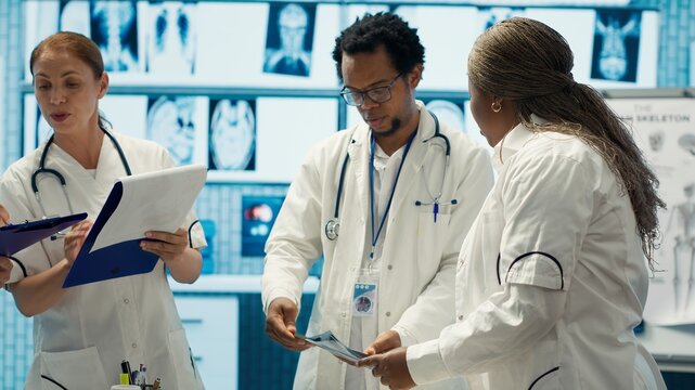 Group of healthcare workers analyzing diagnostic data and planning treatment in a private clinic, emphasizing collaboration. Coordinating recovery plans after recent test results. Camera A.