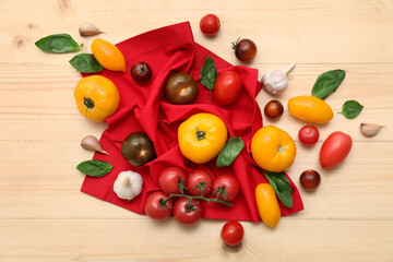 Different fresh tomatoes with garlic and basil on wooden background