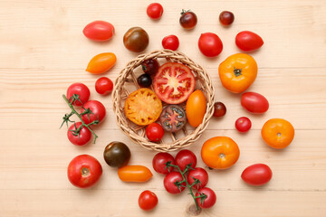 Wicker bowl with different fresh tomatoes on wooden background