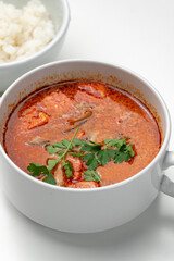 Bowl of curry with pieces of meat and a side of steamed rice arranged neatly for a meal