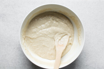 Overhead view of nigerian puff-puff dough that has proofed, puff-puff dough in a white mixing bowl, process of making puff-puff or bofrot