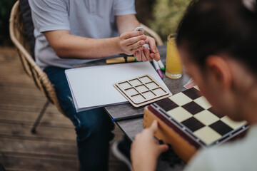 Individuals enjoying a strategic board game on a wooden deck. Focus on teamwork and critical...