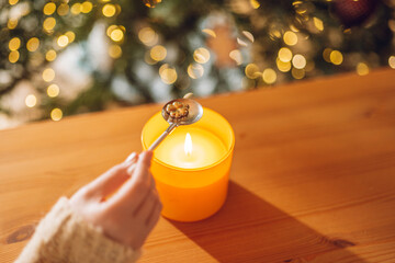 Fortune telling with melting tin. tin clover figurine in spoon over candle flame in a hand on...