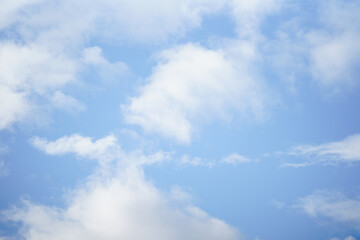 A serene sky filled with soft, fluffy clouds drifting across a bright blue background, creating a peaceful and uplifting atmosphere perfect for nature-themed designs.