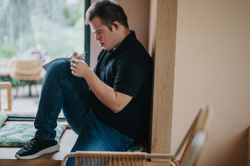A young man with Down Syndrome is thoughtfully writing in a serene indoor setting, emphasizing...
