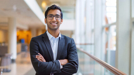 Confident young professional standing with arms crossed in a modern office, symbolizing leadership, success, and career ambition