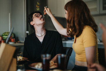 A young couple enjoys a playful moment while sharing a meal at home. The scene captures intimacy and joy in a casual dining setting, highlighting companionship and happiness.