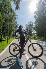 Obraz premium Caucasian woman riding a bike in a park. Vertical photo. 