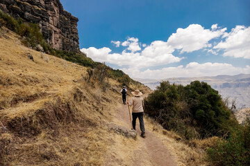 Dos turistas caminando por un sendero en camino a Wakrapukara en Cusco, Perú