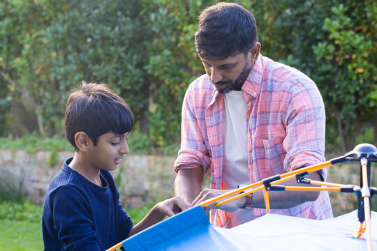 Setting up tent, Indian father and young son enjoying outdoor activity together