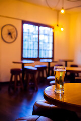 Glass of Beer on Wooden Table in Cozy, Dimly Lit Bar