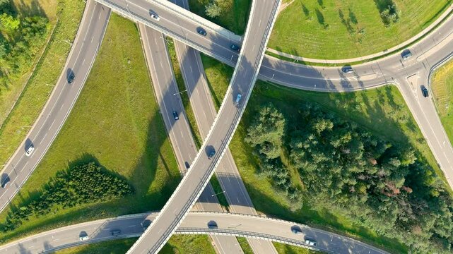 Aerial rotating top-down view of three level road junction. Bright summer urban landscape.