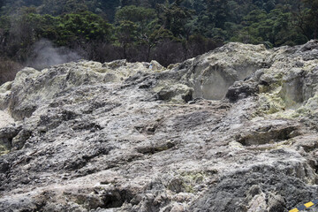 A detailed capture of rocky terrain with visible sulfur deposits and steam rising from the ground, showcasing a geothermal environment. Perfect for nature or environmental science themes