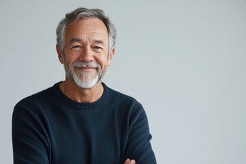 Obraz premium Half body shot of an older male presenter with a warm smile, in front of a solid light gray background, with copy space