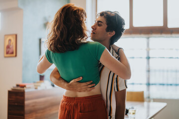 A young couple shares a warm embrace in a cozy home setting, conveying love and affection. Sunlight...