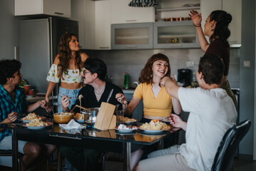 A lively group of friends sharing a meal in a modern kitchen. The atmosphere is joyful, reflecting friendship and togetherness over a delicious dinner.