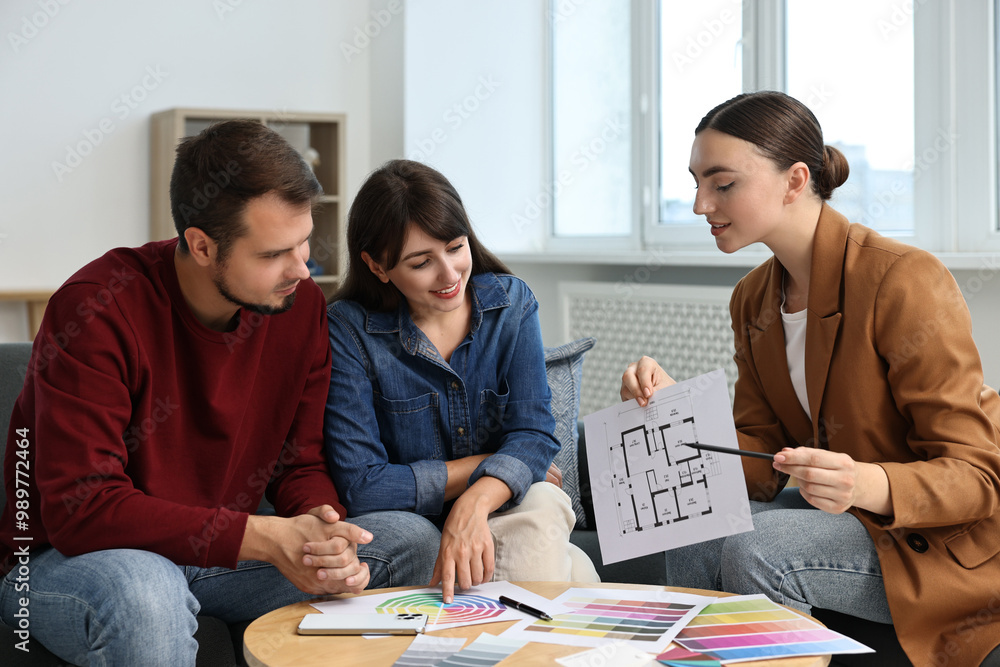 Poster designer discussing project with clients at table in office