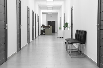 Empty hospital corridor with chairs and doors