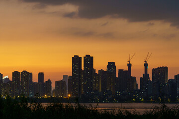 Naklejka premium Wuhan Dusk: Orange Glow Over Modern City