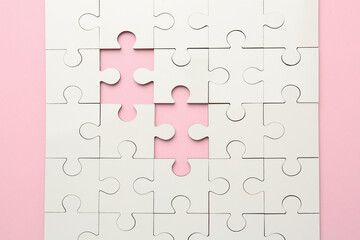 White puzzle with missing pieces on pink background, top view