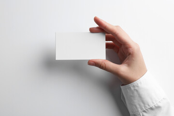 Woman with blank business card on light grey background, closeup. Mockup for design
