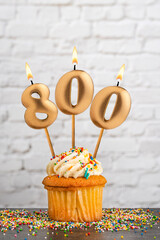 Cupcake with number 800 birthday candle - White block wall background