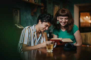 Two friends share a joyful moment, laughing and reading together at a cozy cafe. Young adults enjoying quality time with books and tea in a relaxed setting.