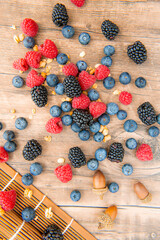 Blueberries and raspberries, blackberry in a wooden carpet on old wood background, copy space for text