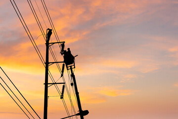Silhouette of Electrician officer climbs a pole and uses a cable car to maintain a high voltage...