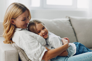 Mother and daughter sharing a joyful moment on a cozy couch in a bright and inviting living room