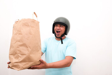 Portrait of Asian online courier driver wearing tshirt and helmet giving craft paper shopping bag with gift inside. Isolated image on white background