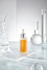 A minimalist photo template featuring a turmeric yellow serum dropper bottle, water droplets, laboratory glassware, and a glass ball on a white background, ideal for advertising skincare products.