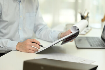 Cropped shot smiling young businessman checking financial document at desk
