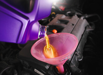Engine oil is poured into the funnel by car mechanic for lubricating the engine , motor oil change...