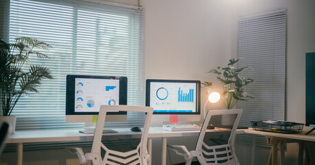Two computer monitors on a desk displaying graphs in a well-lit office, suggesting a focus on data analysis and business strategy