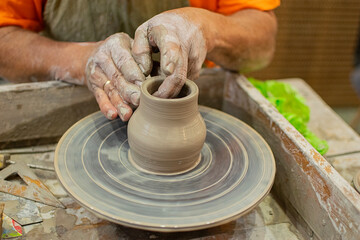Close-up of a potter's hands creating a ceramic vase on the craft wheel. © Sergio Palacio