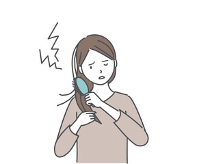 傷んだ髪をブラシでとかす女性