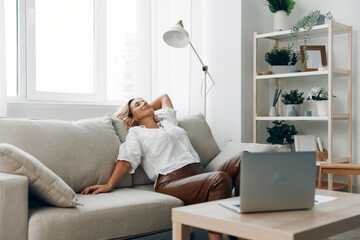 Woman relaxing on couch with laptop and coffee table, enjoying a casual day indoors