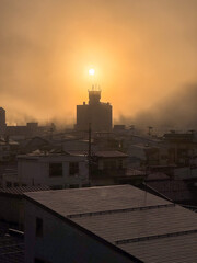 Sun rising over a misty city skyline.