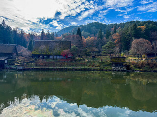 Fototapeta premium Traditional Japanese village reflected in a serene lake.