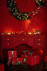 Festive living room interior in red colors with Christmas decorations, boxes with gifts and a wreath on the wall. High quality photo