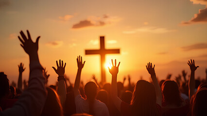 Hands raised in worship in front of a cross at sunset