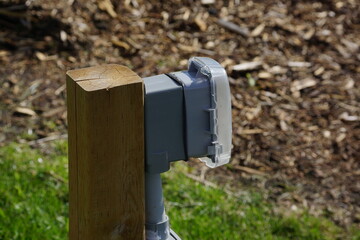 Outdoor outlet with protective cover on grass and wood bark chips