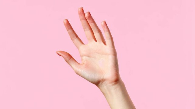 A hand reaches out, fingers spread wide, against a soft pink background