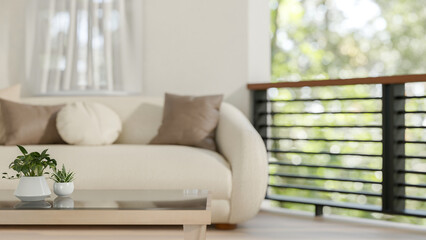 A close-up of a coffee table in a comfortable living room, featuring a modern sofa and a balcony.