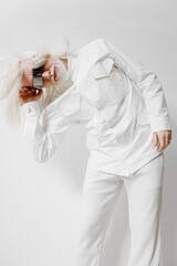 Fashionable model with white hair in a striking pose, wearing a stylish white outfit, showcasing creativity and uniqueness against a plain light background