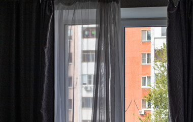 A window with a curtain open and a view of a city