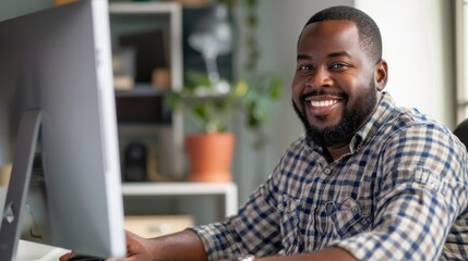 Obraz premium A man is sitting in front of a computer monitor with a smile on his face